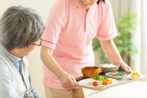 aide soignante qui apporte un repas 